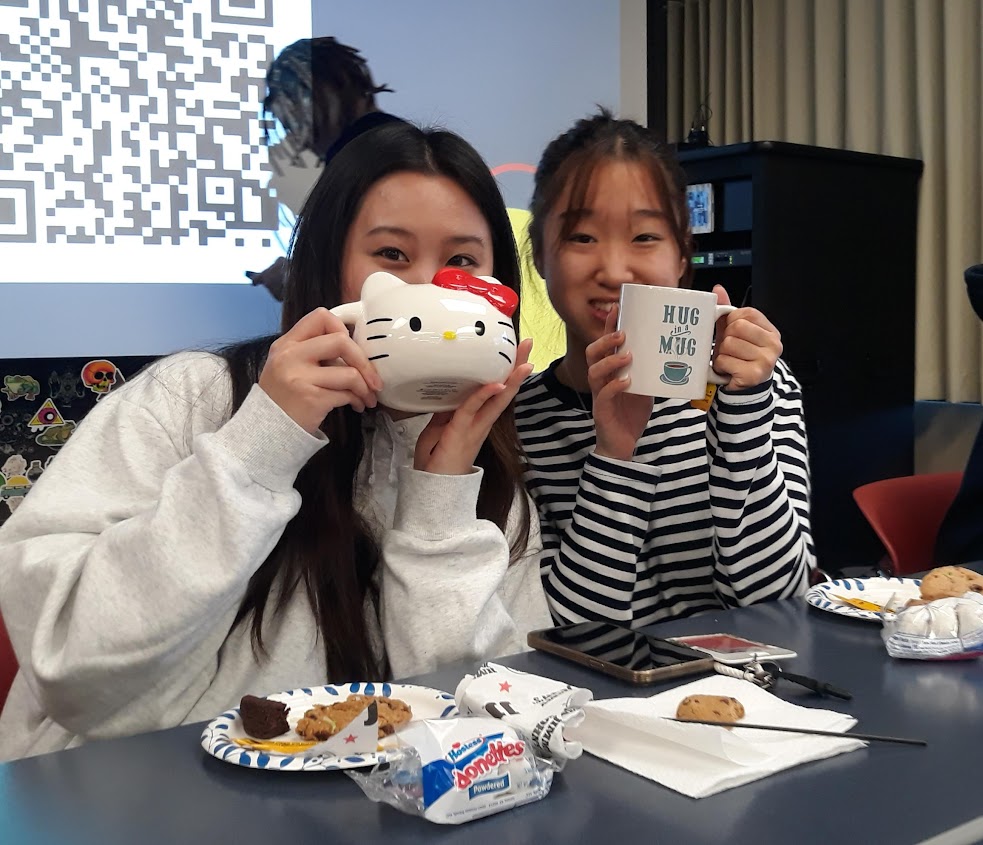 Two students posing with their mugs