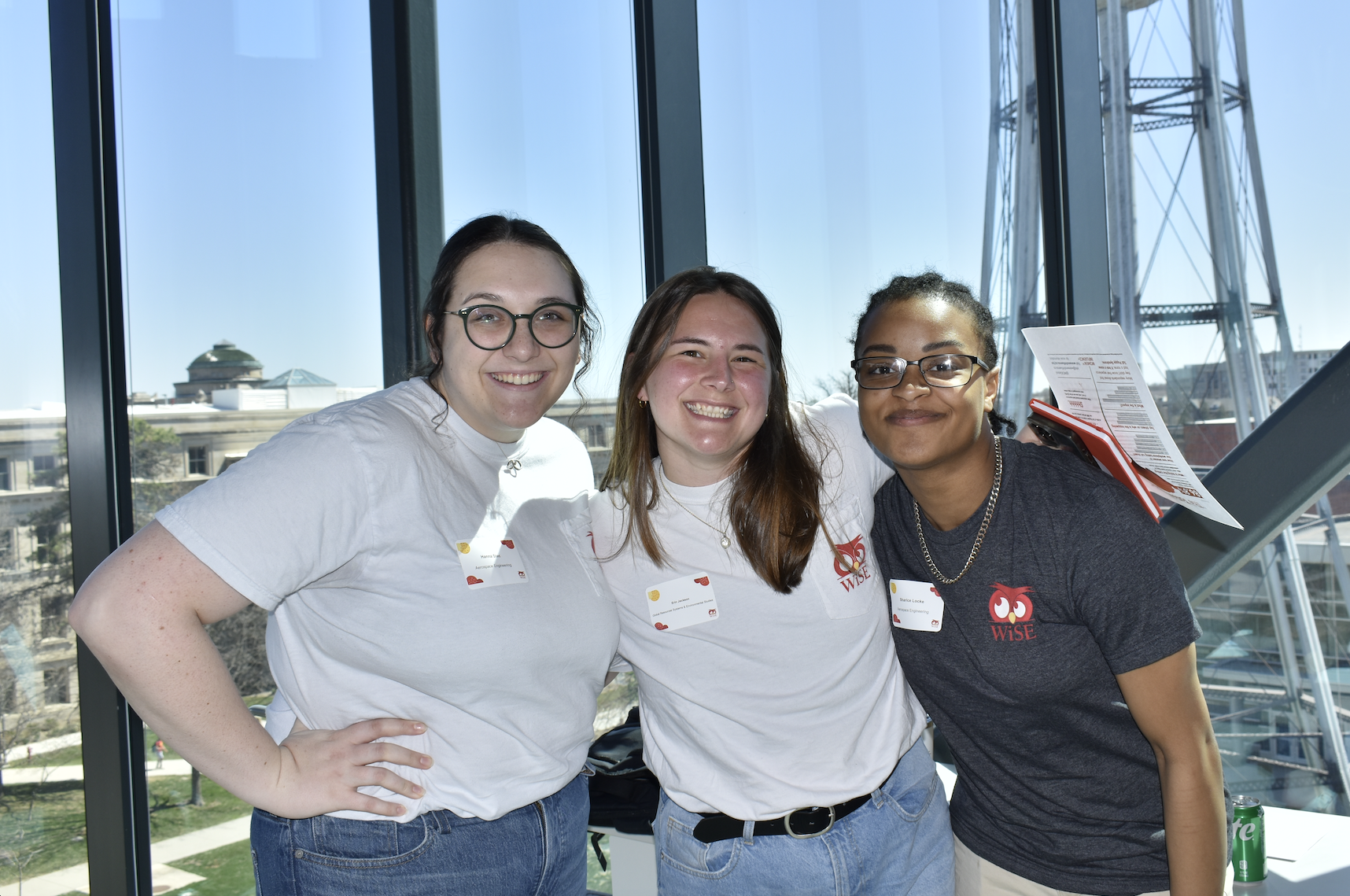 Three students smiling at the camera, arms around each other